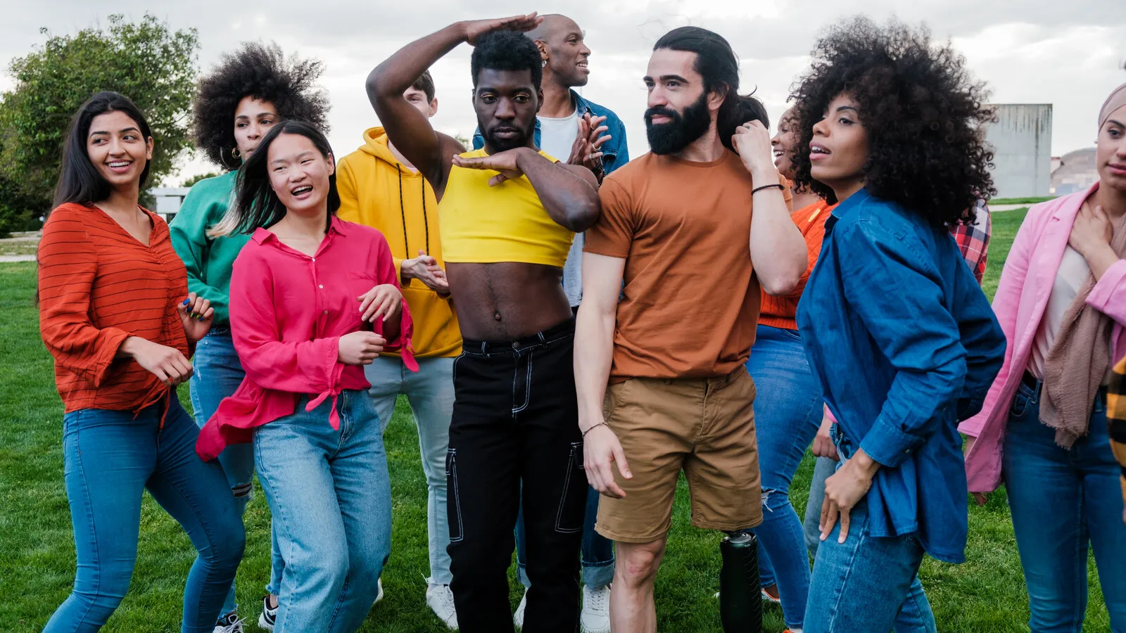 A group of friends posing together outdoors on a green field, faces warm and at ease in afternoon light.