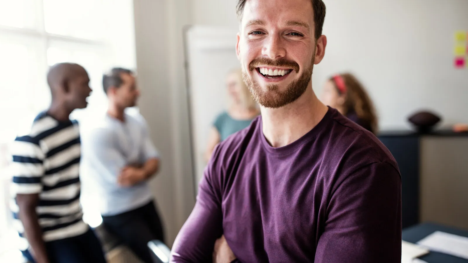 A young person laughing standing in a bright office-like space, comfortable and energized.